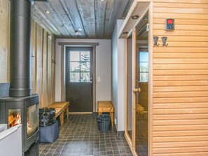 A room with a wood-burning stove, a bench, a door, and a window.