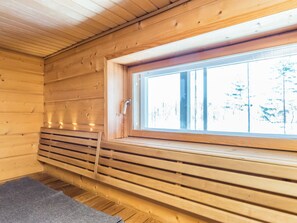 Ein Blockhaus-Interieur mit einer hölzernen Liegebank, einem Fenster und einer Tür.
