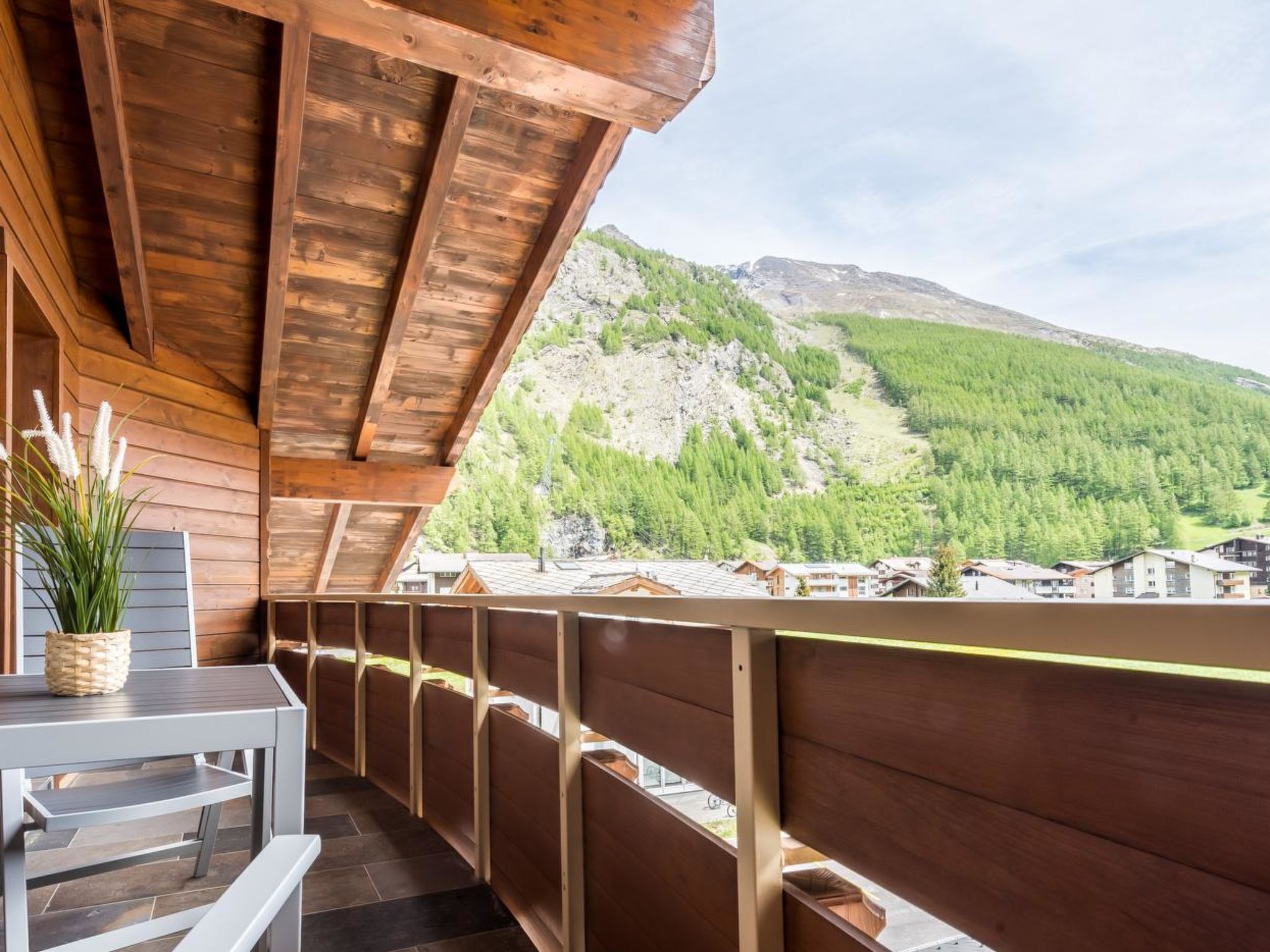 A wooden balcony with a view of a mountain and buildings.