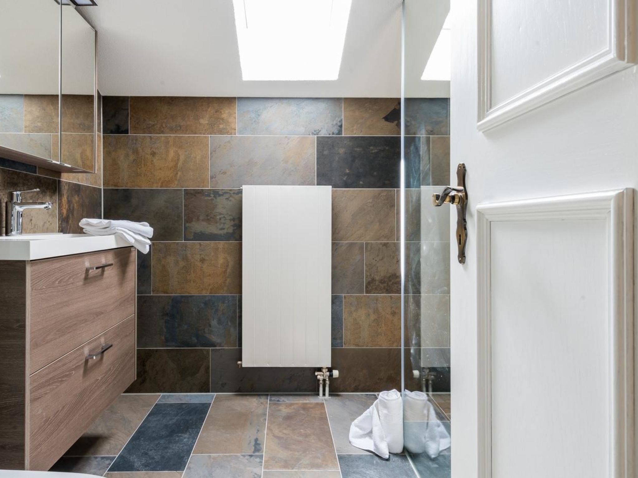 A modern bathroom with a shower, a sink, and a towel rack.