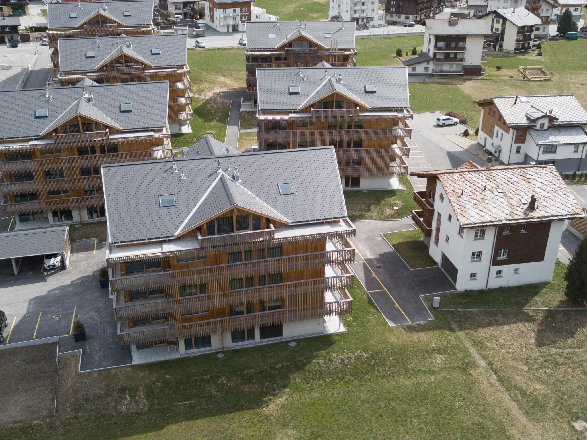 Un ensemble d’immeubles modernes à plusieurs étages, dotés de balcons, d’un espace de stationnement et d’un aménagement paysager verdoyant.