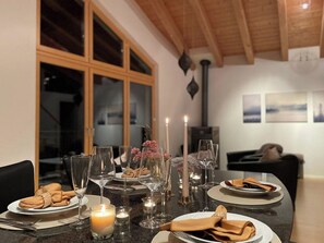 Una mesa de comedor con platos, vasos y velas, con vistas a una sala de estar y una chimenea al fondo.