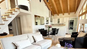 Ein modernes Interieur mit hoher Decke, einem Essbereich und einer Treppe.