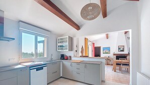 Une cuisine moderne dotée d’une grande fenêtre, de placards intégrés et d’un coin repas avec une table et des chaises.