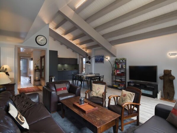 Ein modernes Wohnzimmer mit hohen Decken, einem Essbereich, einer Küche und einem Fernseher.