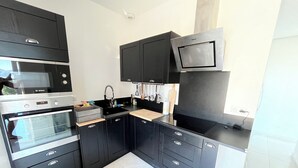 Una cocina moderna con armarios negros, un horno Bosch, un lavaplatos y un microondas.