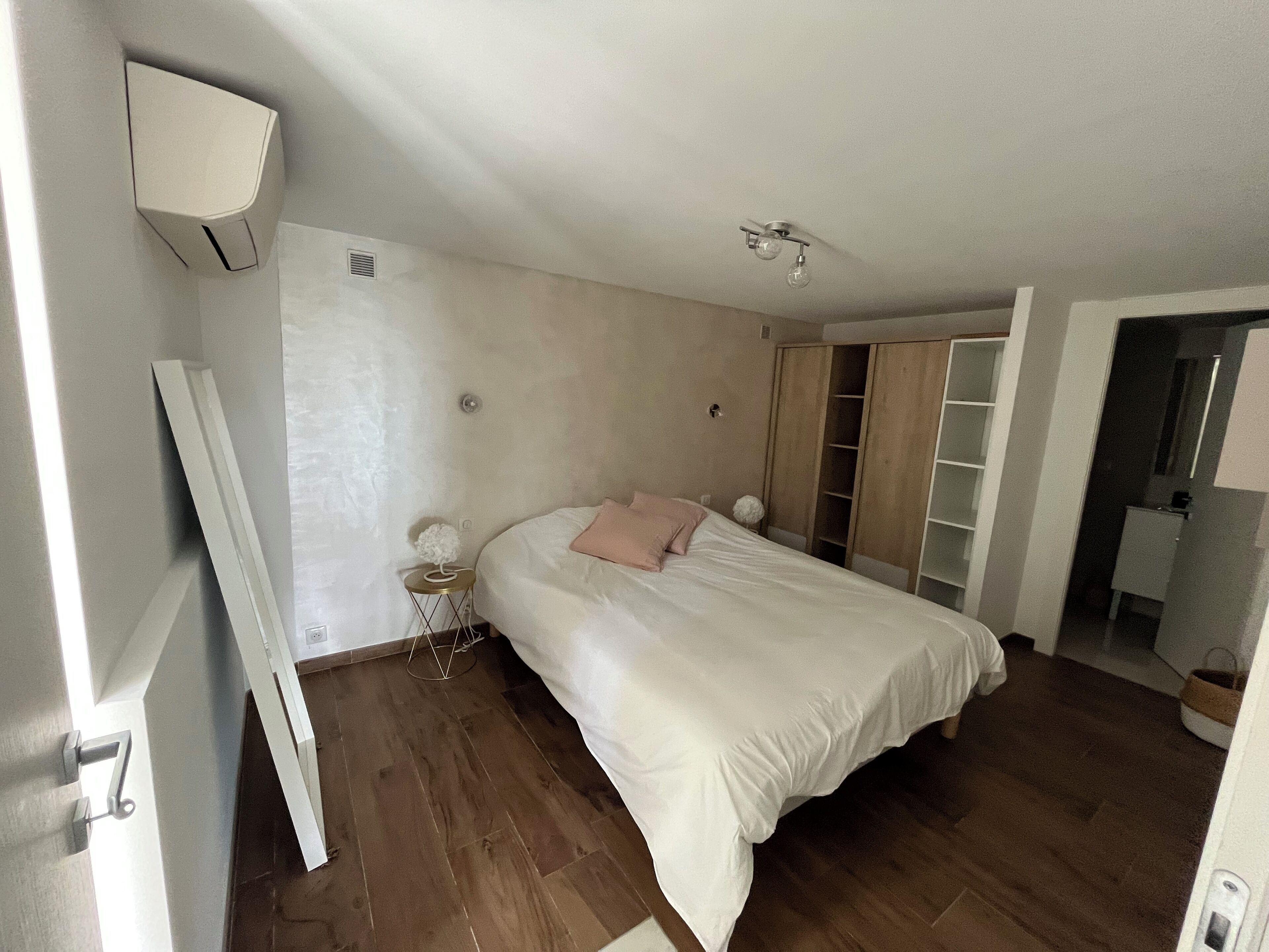 A bedroom with a bed, a wardrobe, a mirror, and a ceiling fan.