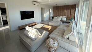 Una sala de estar moderna con un televisor de pantalla plana grande, un sofá y un comedor con una pared de madera.
