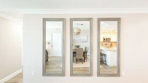 Ein Flur mit drei Spiegeln an der Wand, der zu einem Essbereich und einer Küche führt.