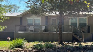 A two-story house with a covered porch, a staircase leading to the upper level, and a small garden area with rocks and plants. - Relax after a Day on the Lake! (Hulbert)