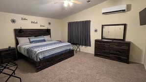 A bedroom with a bed, a dresser, a ceiling fan, an air conditioner, and decorative wall art. - Relax after a Day on the Lake! (Hulbert)
