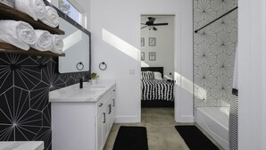 Un baño moderno con un lavamanos blanco, un espejo y una zona de ducha.