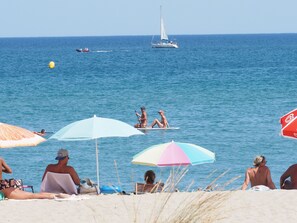 Na praia, espreguiçadeiras, toalhas de praia 