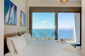A bedroom with a large bed, a view of the sea, and a balcony with a table and chairs. - Villa Akri-Blue Spirit near Almyrida 4BD 4B (Almirida)