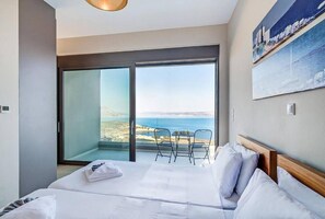 Habitación de hotel con una cama grande, vistas al mar y un balcón con sillas.