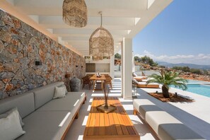 Un espace de vie extérieur moderne, agrémenté d’un mur en pierre, de mobilier en bois et d’une piscine.