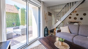 A modern living room with a grey sofa, a wooden coffee table, and a staircase leading to an upper level.