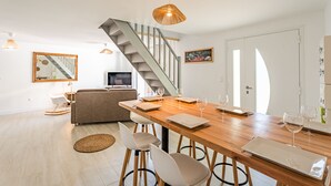 A modern living space with a wooden dining table, a sofa, and a staircase.