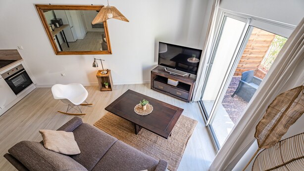 A modern living room with a sofa, coffee table, TV, and a dining area.