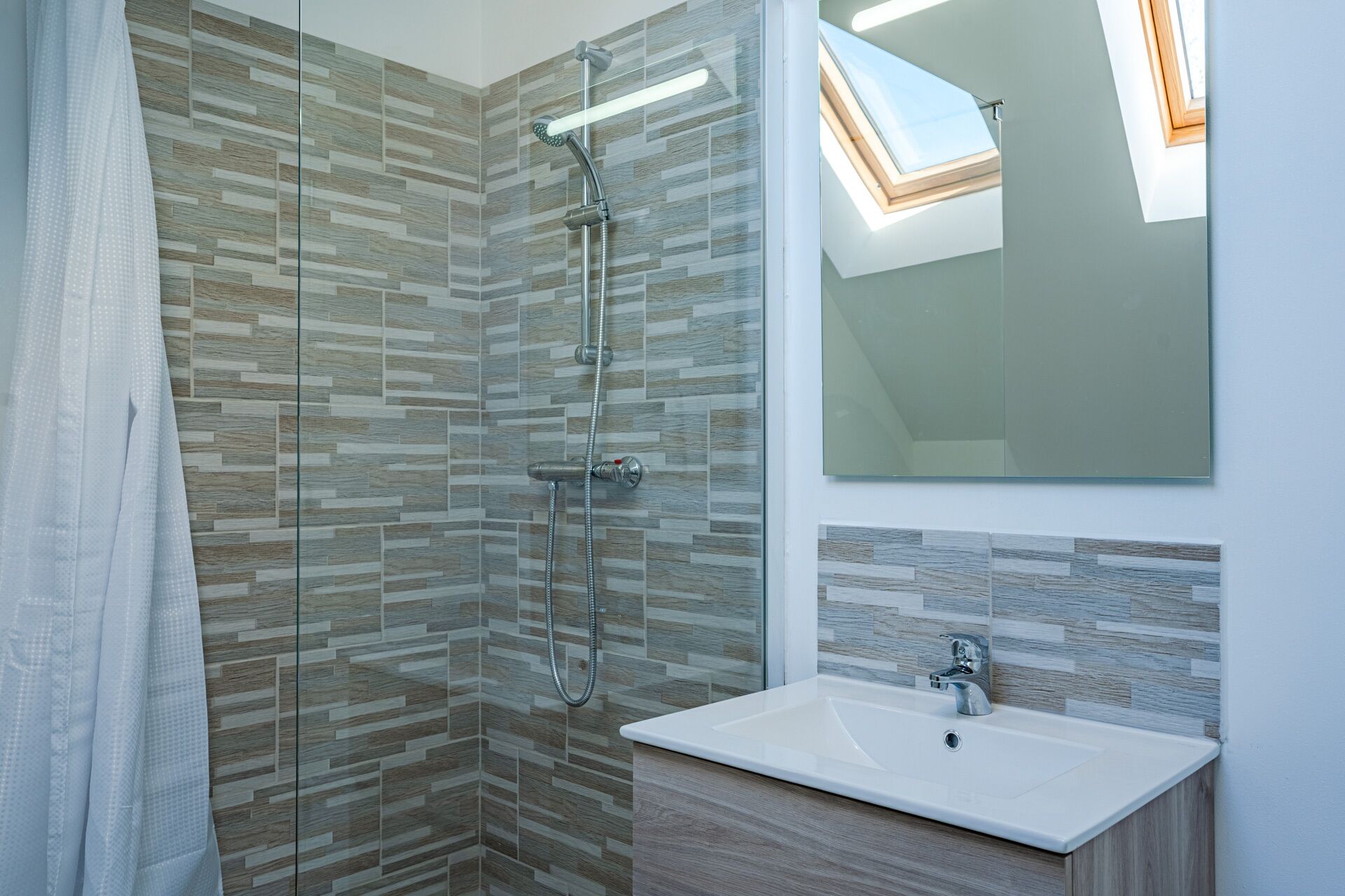 Un baño moderno con ducha, lavabo y espejo.