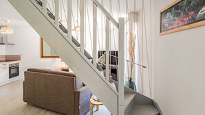 A modern interior with a staircase, a sofa, and a painting.