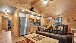 A cozy cabin interior with a wooden ceiling, a kitchenette, a sofa, and a dining table. - Cabin # 3 at Northern Comfort w/opt side by side rentals (Atlanta)