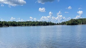 A calm lake with clear water reflecting the sky, surrounded by a forested area. - Escape to Paradise: Your dream vacation awaits in our stunning lakefront rental! (Tomahawk)