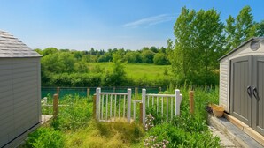 A view of a property with a wooden fence, a shed, and a pond.