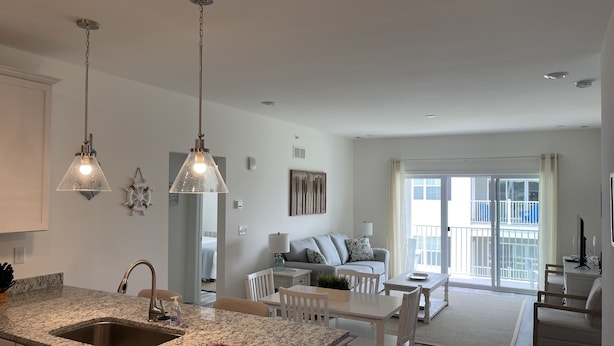 A modern kitchen with granite countertops, a sink, and two pendant lights. - Condo on Rehoboth Bay close to beaches and boating (Lewes)