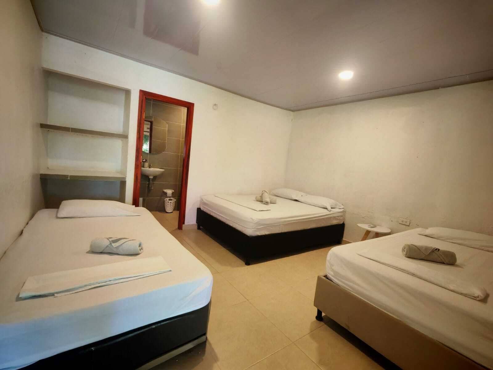 Ein kleines, sauberes Zimmer mit zwei Betten, einem Waschbecken und einem Spiegel.