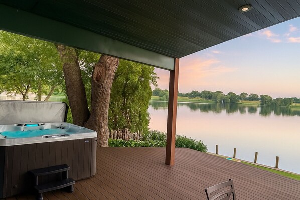 Un jacuzzi en una terraza de madera con vista a un lago y árboles.