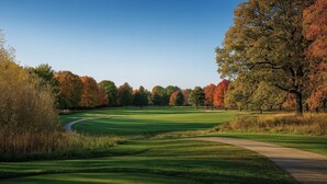 Een golfbaan met een duidelijke route, omringd door bomen met herfstbladeren.