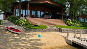 A lakeside cabin with a covered deck, a dock, and a kayak.