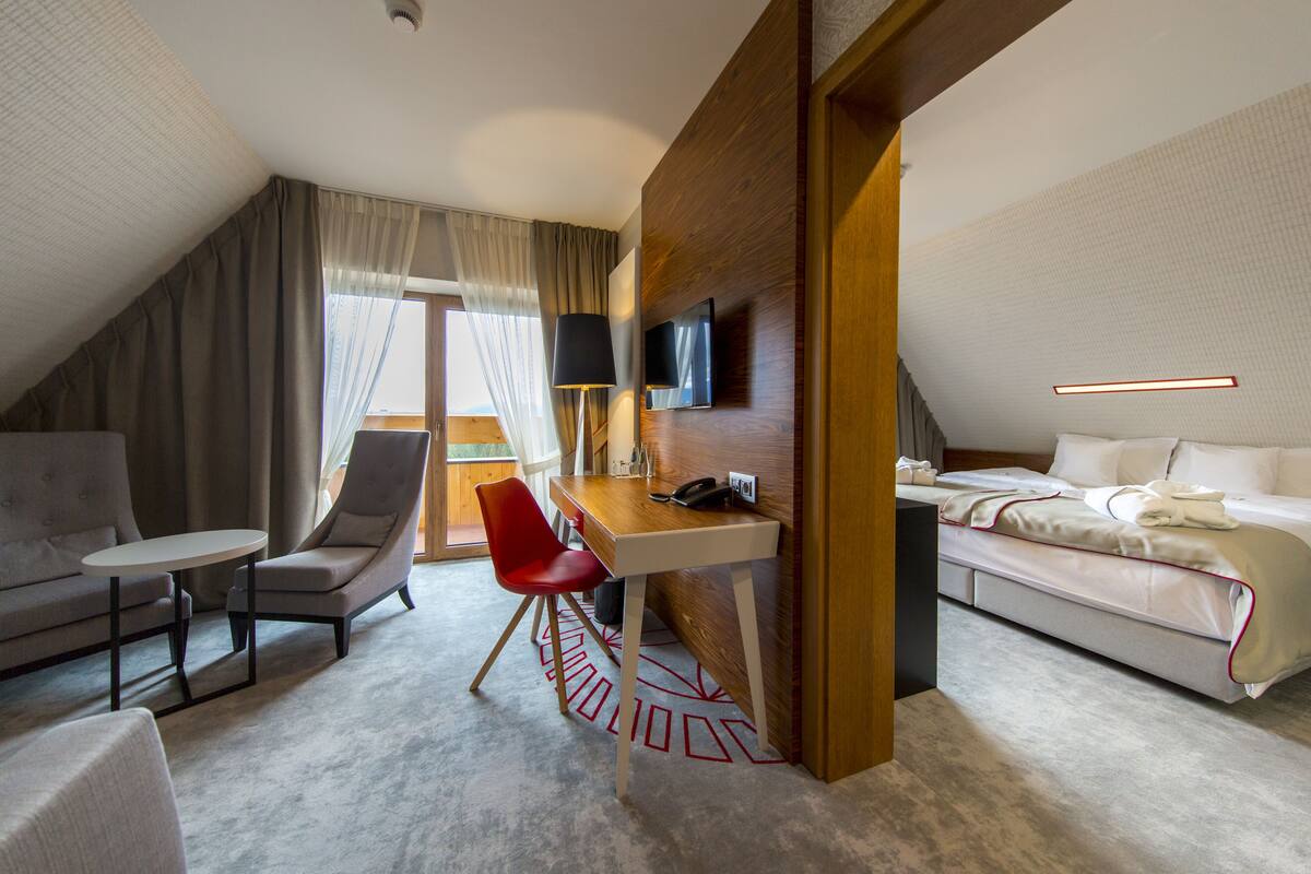 Una habitación de hotel con cama, escritorio, silla, sofá y televisor.