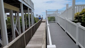 Un muelle de madera con barandillas blancas que conduce a un edificio con balcón.