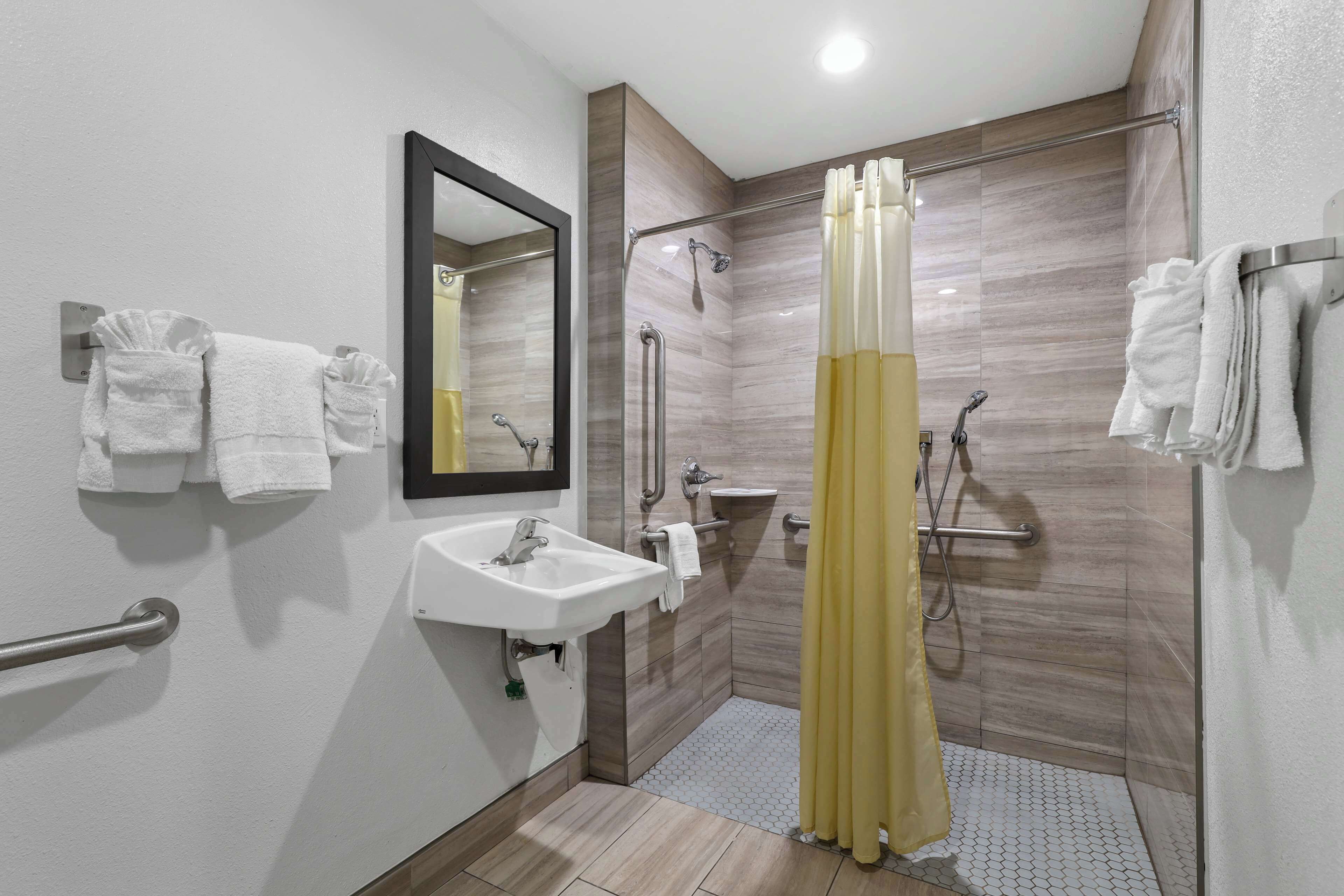 A modern bathroom with a walk-in shower, a sink, a mirror, and a towel rack.