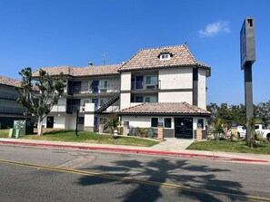 A multi-story residential building with a tiled roof, a front entrance, and a parking area. - Studio 6 Suites Escondido, CA (Escondido)