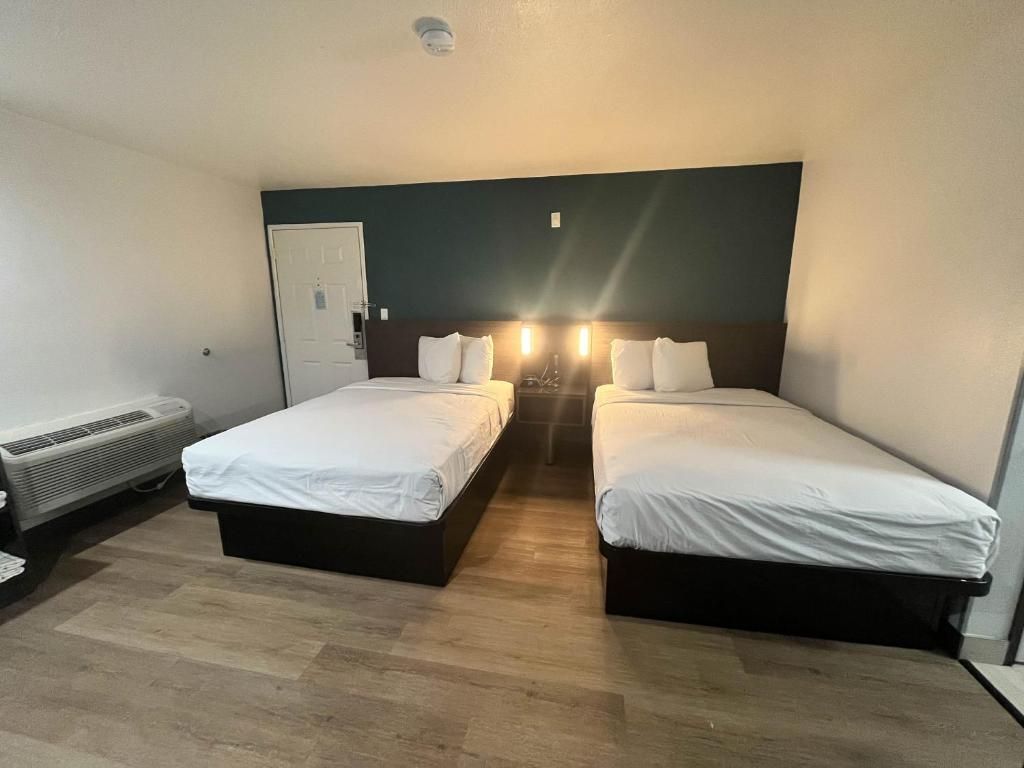 A hotel room with two single beds, a heater, and a door.