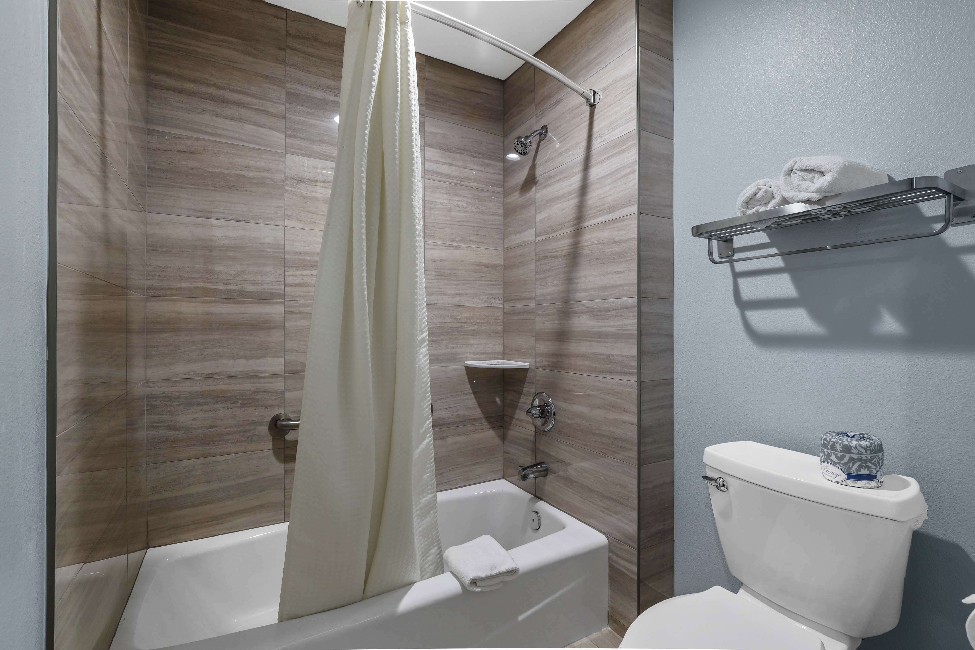 Een badkamer met een bad, douche en toilet.