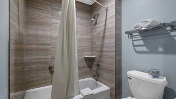 Een badkamer met een bad, douche en toilet.