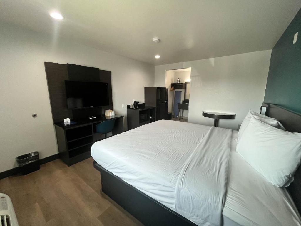 A modern hotel room with a large bed, a flat-screen TV, a desk, and a small table.