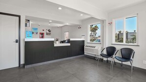 A reception area with a counter, two chairs, a window with a view, and a door. - Studio 6 Suites Escondido, CA (Escondido)