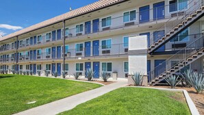 A multi-story motel with a central courtyard, featuring a modern design with blue doors and a staircase on the right. - Studio 6 Suites Escondido, CA (Escondido)