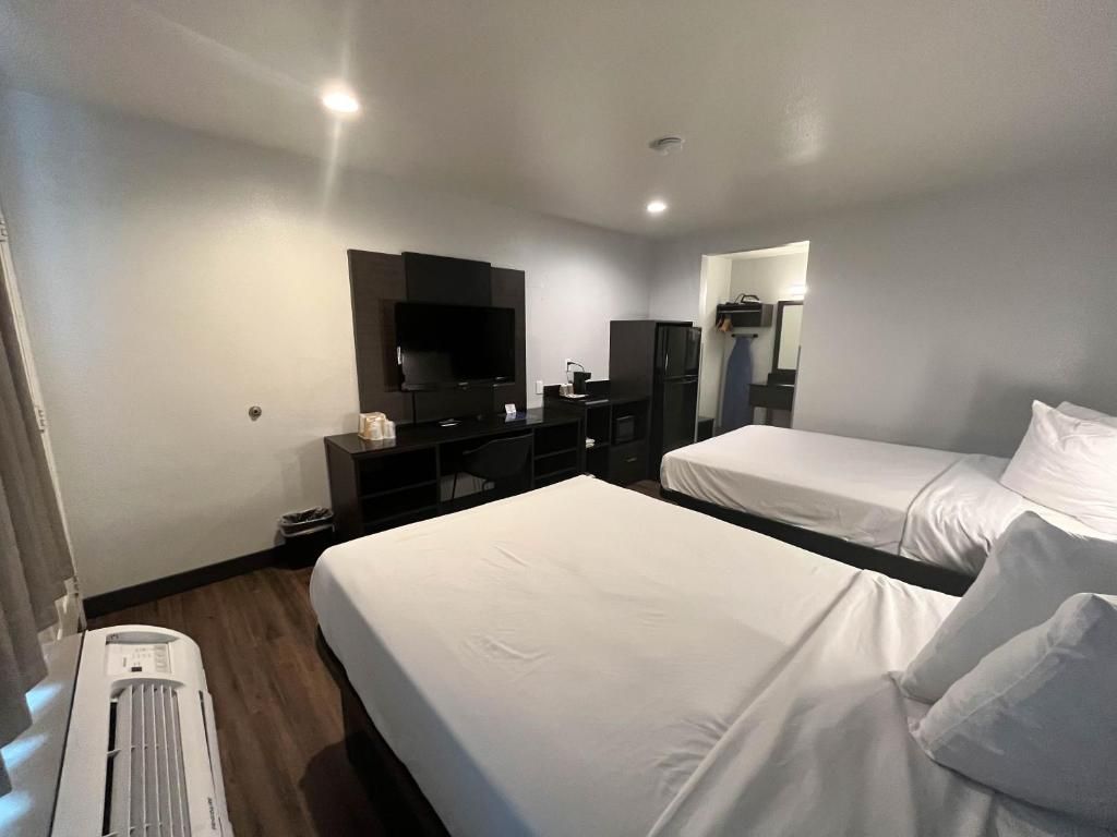 A hotel room with two beds, a desk, a television, and a mirror.