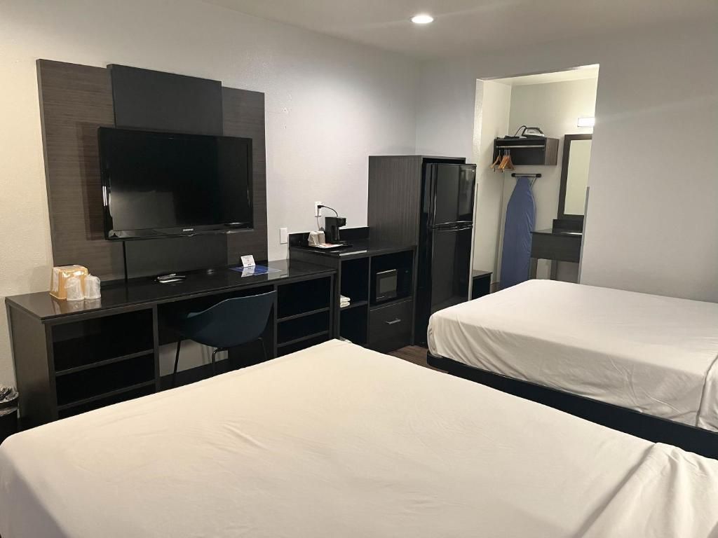Una habitación de hotel con cama, escritorio, televisor y armario.