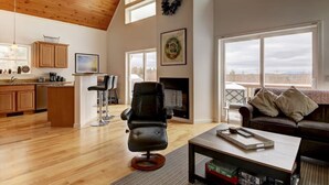 A spacious living area with a fireplace, a kitchen with wooden cabinets, and large windows offering a view of the outdoors. - Tranquil mountain view home near downtown North Conway
Mountain Views. Cable TV. (Madison)