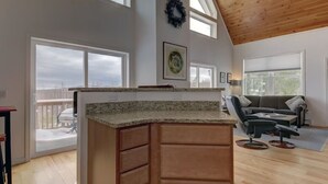 A spacious living area with a large wooden ceiling, a kitchen with granite countertops, and a balcony with a view. - Tranquil mountain view home near downtown North Conway
Mountain Views. Cable TV. (Madison)
