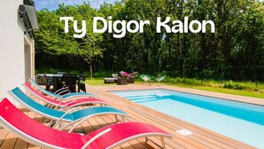 Zona piscina con poltrona a sdraio e tavolo, immersa nel verde.