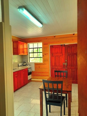 Enjoy meals at the dining table near the window, with a stove and cabinets nearby for food preparation.