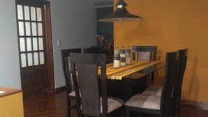 Un comedor con una mesa de madera, cuatro sillas y una lámpara colgante.